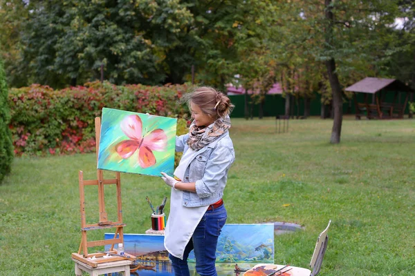 Artista donna tiene la pittura e la guarda, posa davanti alla macchina fotografica un — Foto Stock