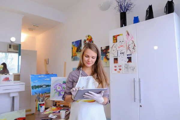 Cute Girl tient et utilise la tablette. Artiste de l'apparition européenne dans — Photo