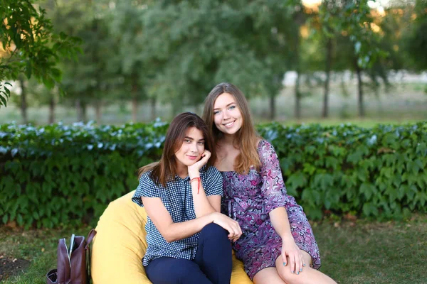 Dos chicas atractivas sentadas una al lado de la otra en silla, smilin — Foto de Stock