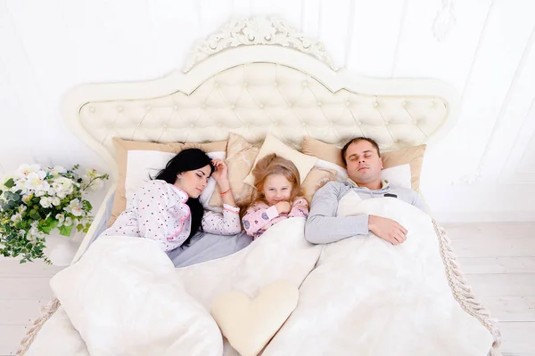 Gelukkige familie liggen in een witte bed en slaap. Moeder, vader en — Stockfoto