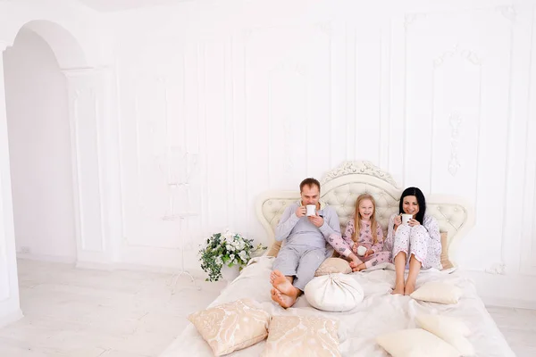 Mutlu aile içecek çay veya kahve gülümseyen ve seyir pijama
