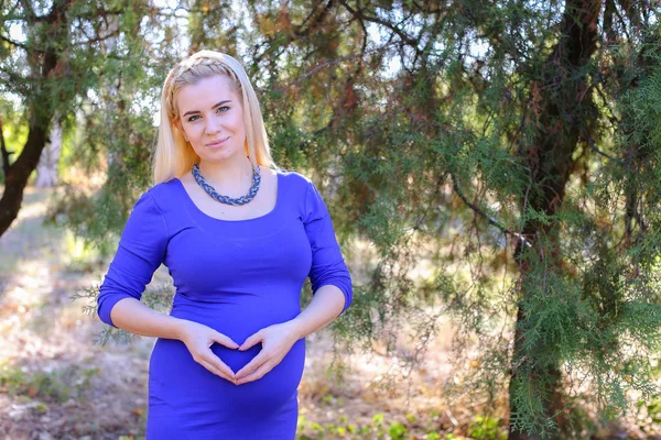 Hübsche schwangere Frau lächelnd, sanft streichelnd Bauch und zeigt — Stockfoto