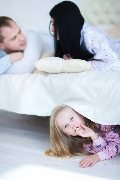 Filha escondida debaixo da cama, mamãe e papai falaram em casa — Fotografia de Stock