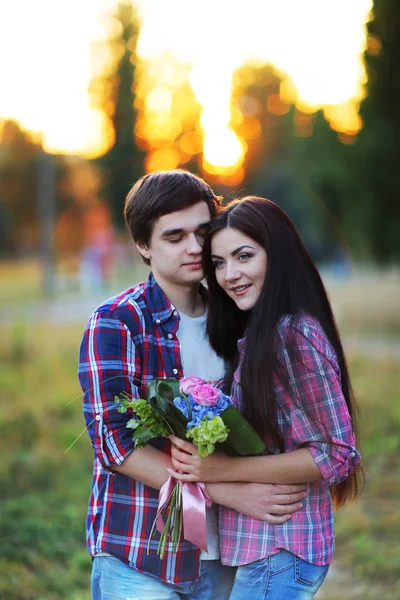 Jovem casal bonito abraçando e sorrindo ao pôr do sol no verão — Fotografia de Stock