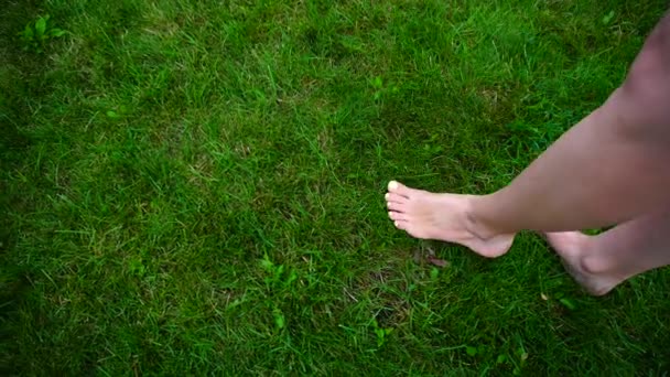 Primeros planos de los pies de la joven que lleva un pie en la hierba al aire libre en el día . — Vídeos de Stock