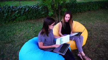 Genç kızlar Denetçiler öğleden sonra yumuşak koltuklar defada Park açık bilgisayarlarda çalışan kuruluş faaliyetleri kontrol.