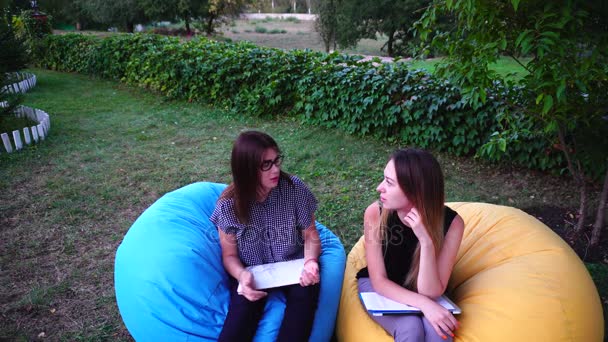 Mignonnes copines commérages tandis que assis dans le parc en plein air le jour de l'été . — Video