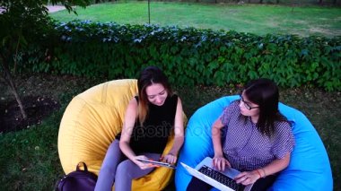 İki kız medya planlamacılar reklam Pazar değişiklikleri izlemek ve bilgisayar ve Park açık havada koltuklarda oturan Tablet bilgi girmek.