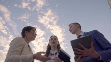 Eğitimli insanlar konuşmak, sıkışalım, tutun, eller klasörlerde Stand yakın gökyüzü açık havada nötr renklerde arka plan üzerinde İş Merkezi.