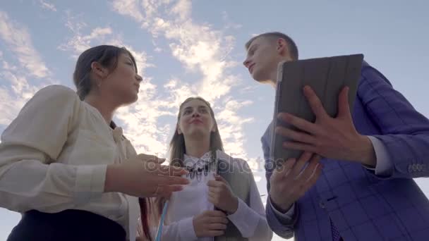 三个青年实业家聊友和颤抖的手，站在户外的中性色的天空背景上的商务中心附近. — 图库视频影像