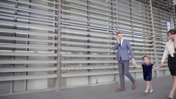 Pretty Family, Female and Guy Talking on Phone and Lead by Hand Baby Girl, Walk Together Along Outdoors of Business Center in Neutral Colors. — Stock Video