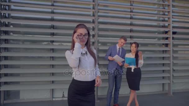 Mujer de negocios segura tomó un descanso del trabajo, sonriendo y posando en la cámara en el fondo de colegas cerca del centro de negocios en colores neutros . — Vídeos de Stock