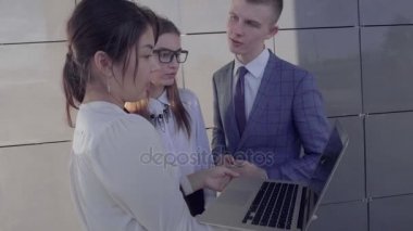Öğrenciler iki kız ve erkek tutuşsun Gadget ve arka plan açık havada nötr renklerde iş merkezinin klasörlerde.
