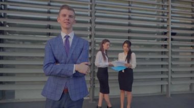 Erkek adam geçti silah ve gülümsüyor, arkadaşları nötr renkler açık havada iş merkezinin penceresinin arka plan üzerinde arka plan üzerinde duruyor.