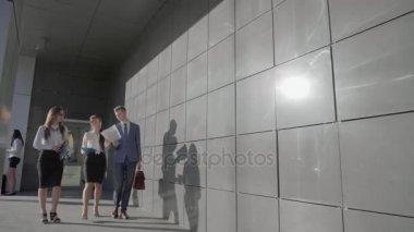 Üç Self-Confident insanlar öğrenci git ve arka plan, duvar ve iş merkezi dış nötr renklerde üzerinde belgeleri ile konuş.