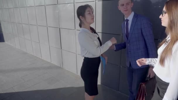 Self-Confident Girls dan Guy Walk and Talk, membawa Tangan Dokumentasi di Latar Belakang Wall of Business Center Di Luar dalam Warna Netral . — Stok Video