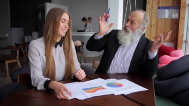 Yaşlı adam kafa genç kadın Yardımcısı gülmek ve Office gülümseme kışın belge okur.
