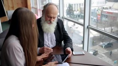 Yeni teknoloji Tablet güzel genç işçi sosyal hizmetler hakkında tavsiye almak için emekli yaşlı adam sorar