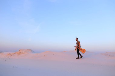 Dese aracılığıyla elinde gitar ile görkemli Müslüman genç adam yürüyor