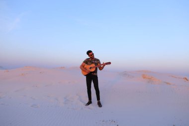 Gitar ayakta bottomle ortasında oynayan yakışıklı erkek Arap