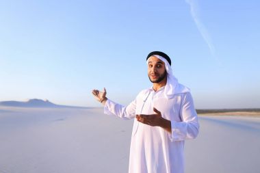 Neşeli Müslüman erkek c yüzünde gülümseme ile çöl üstünde yürür