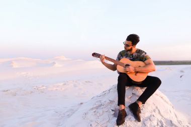 Çekici Arap adam gitar, Hill'de oturan şarkı söylüyor