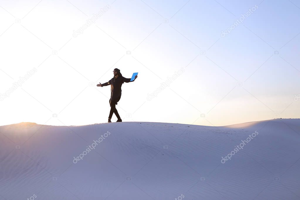 Elevation of male Muslim to top of sand dune over white sand in