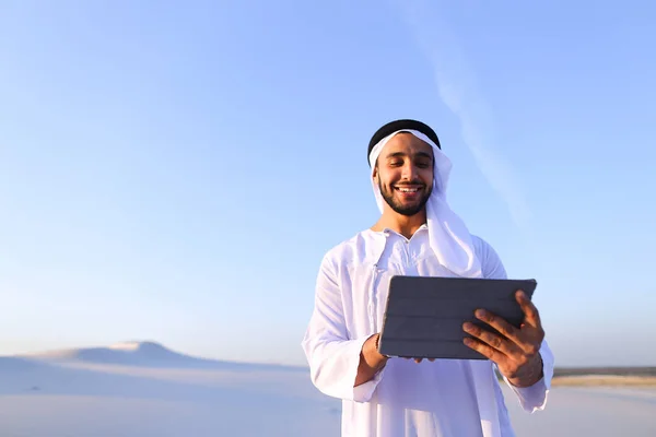 Successful Arabian businessman holds in hands and uses tablet, s — Stock Photo, Image