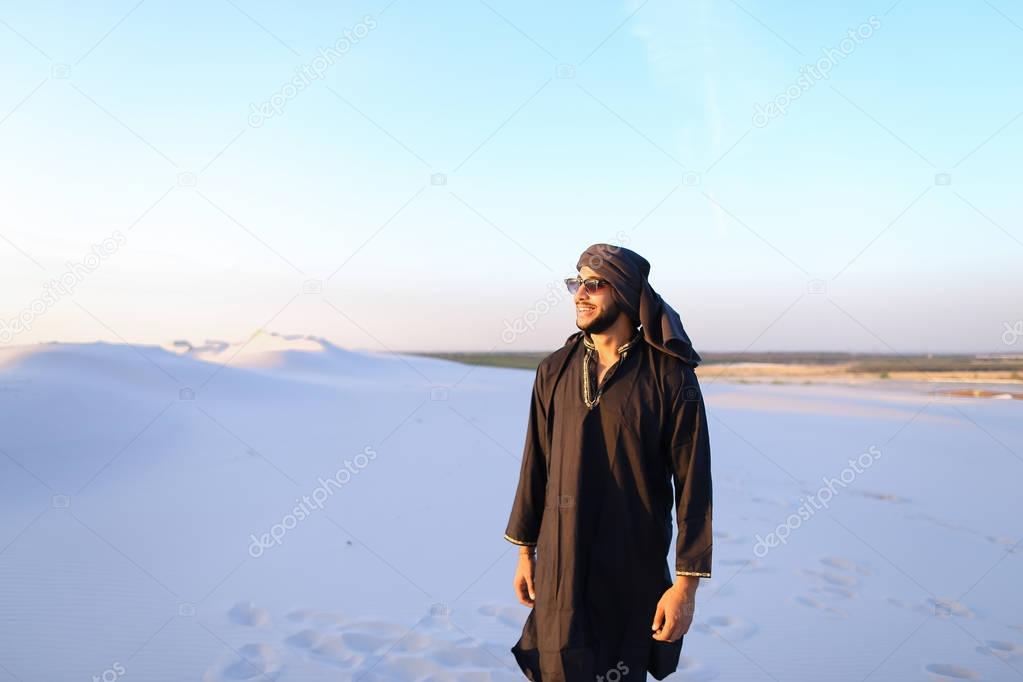 Happy fellow Arabian, walks through desert, smiles and enjoys li
