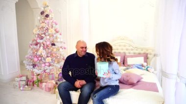 Karısı ve yeni yıl hediye, yatak odası Noel ağacı ile yatakta oturup tanıtımı için kocalar sevgi tezahürü.