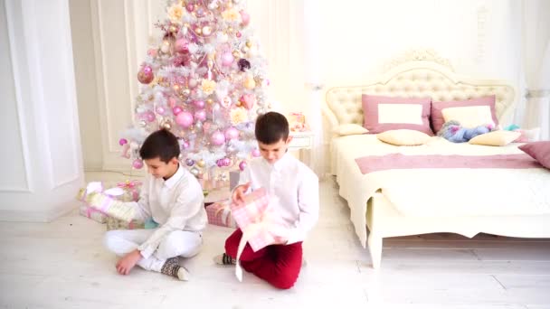 Feliz mañana después del año nuevo y la apertura de los regalos navideños por los niños de los niños en el dormitorio acogedor con el árbol de Navidad . — Vídeo de stock