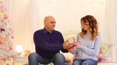 Sunuyu yeni yıl arifesinde tatil Noel ağacı ile yatak odası yatakta oturup iyi ruh hali, aşık çift sunar.