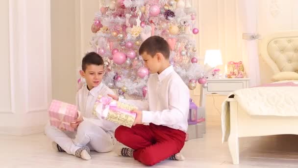 Härliga killar bröder studera gåvor och sitta på golvet i sovrummet med julgran. — Stockvideo