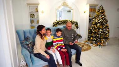 Aile, baba ve koca başkanı arasında eş ve çocuklar, Noel ağacı ile şenlikli bir şekilde dekore edilmiş oda içinde mavi kanepe ve şömine gündüz oturan aile bütçesine dağıtır.