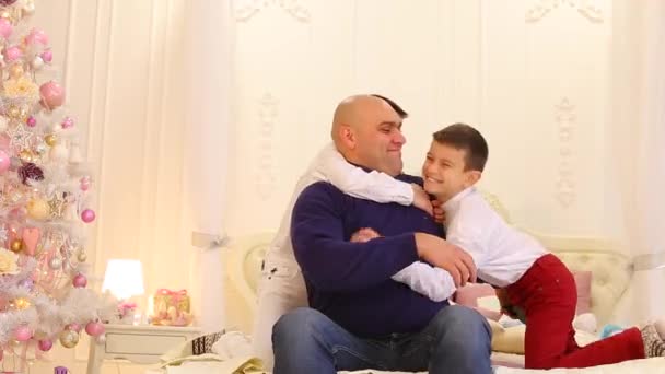 Fun cheerful father and children of twin brothers, on large bed in bright bedroom with Christmas tree. — Stock Video