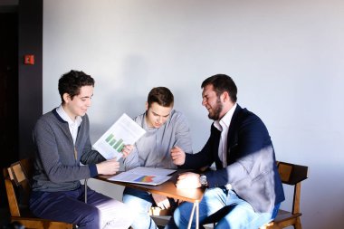 Üç genç erkek programcılar dikkat ederken tablet kullanarak iletişim