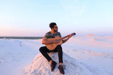 Sevimli genç erkek Arap ses gitar, Hill'de oturan sahiptir