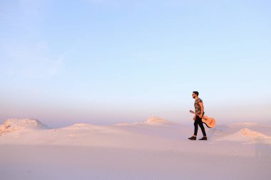 Dese aracılığıyla elinde gitar ile görkemli Müslüman genç adam yürüyor