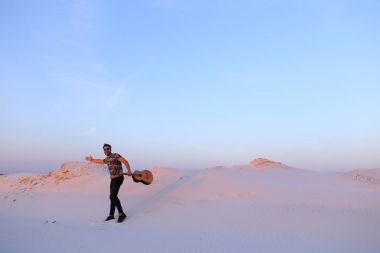 Arap adam çöl güzelliği ile ilham gider ve gitar çi çalış