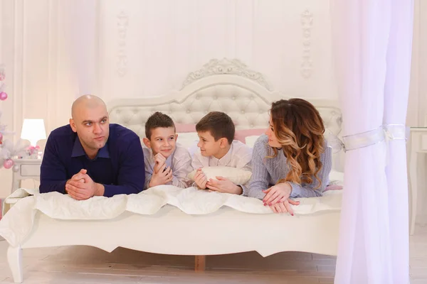 Przyjazny dla rodziny czaty, leżąc na łóżku, Mama i tata z dzieckiem — Zdjęcie stockowe