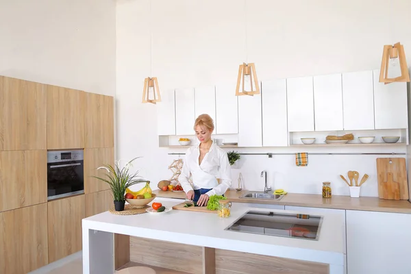 Chica inteligente rebanadas de pepino con cuchillo y sonrisas, de pie en ki — Foto de Stock