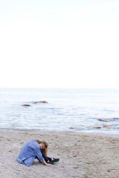 微笑的年轻女子在沙滩上休息和相机，构成坐 — 图库照片