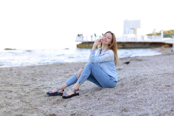 Улыбающаяся молодая женщина отдыхает на пляже и позирует перед камерой, сидя — стоковое фото