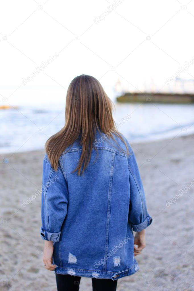 Charming woman with smile poses and walks along sea shore on war