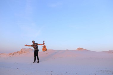 Arap adam çöl güzelliği ile ilham gider ve gitar çi çalış