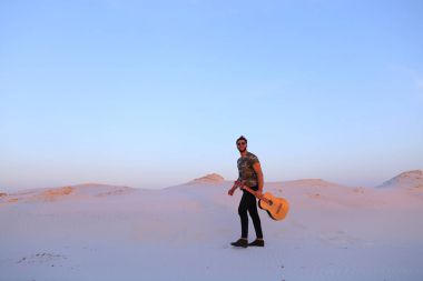 Dese aracılığıyla elinde gitar ile görkemli Müslüman genç adam yürüyor