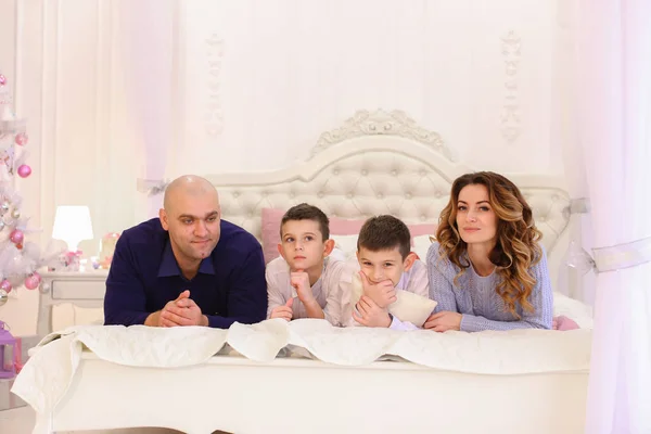 Amigáveis chats familiares deitado na cama, mamãe e papai com seu filho — Fotografia de Stock