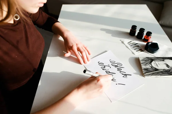 Flicka kalligraf skapar inskription använder brushpen, sitter vid — Stockfoto