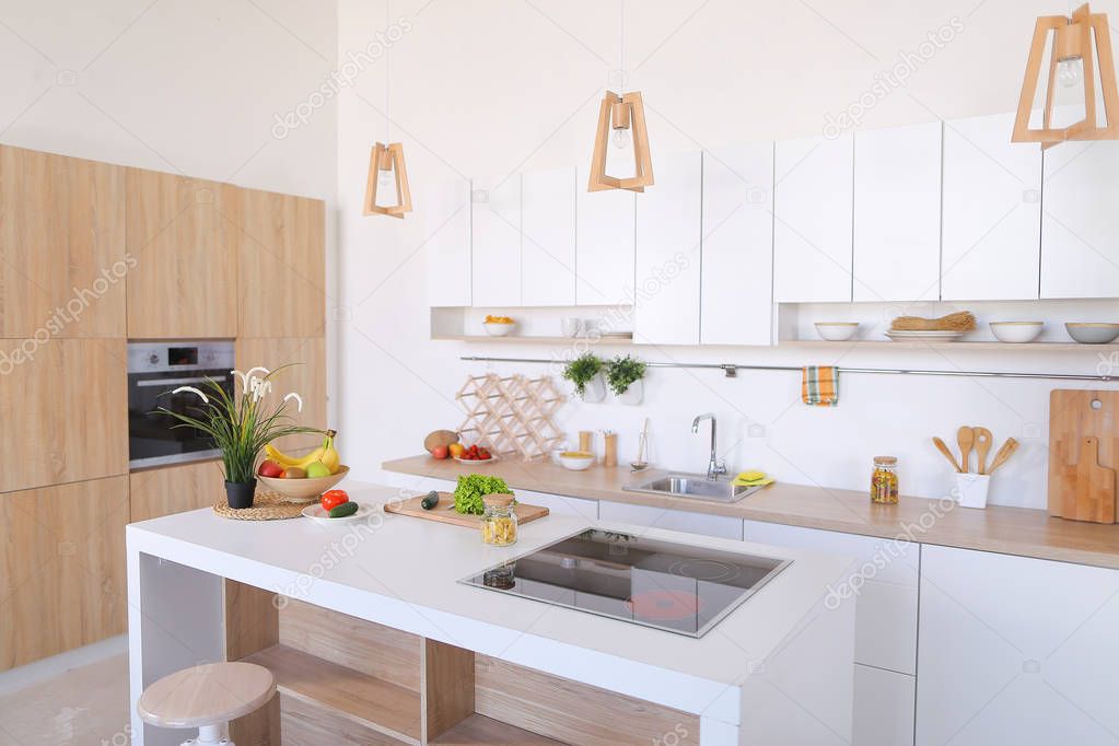 Interior of modern light kitchen with variety of appliances and