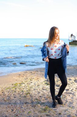 Çekici kız sahil boyunca yürür ve neşeyle kum üzerinde aptallar